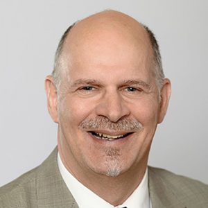 A headshot of Christopher J. Longo smiling at the camera. 