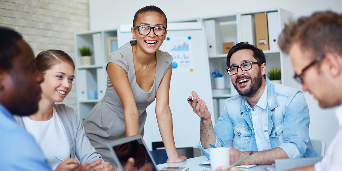 People Working and Smiling Around a Table