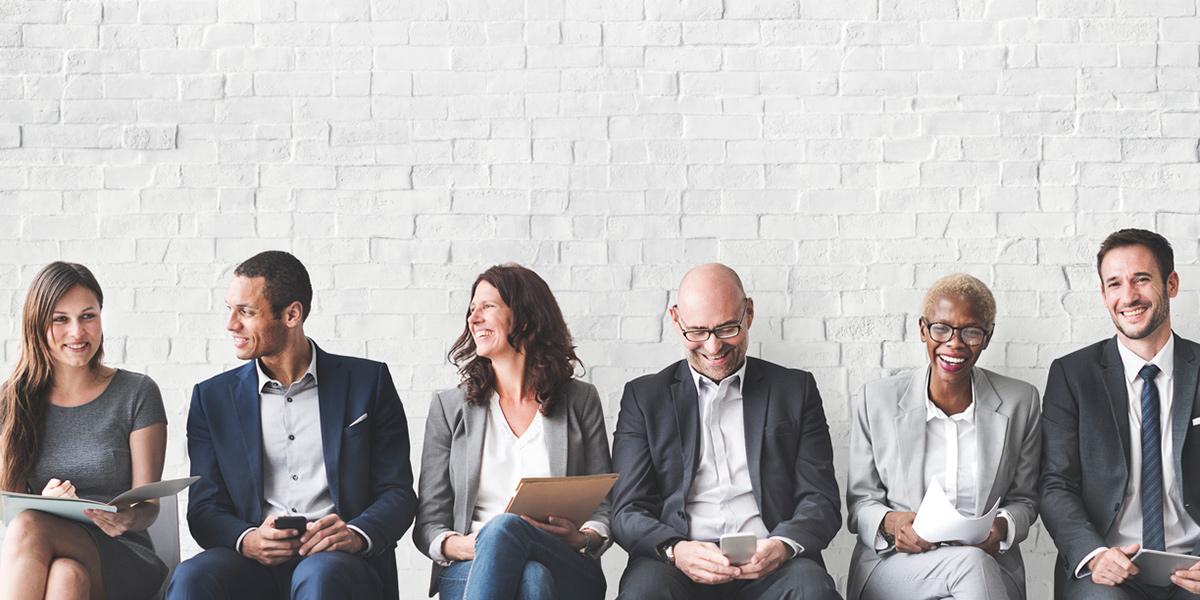 People in Business Clothes Sitting Along a Wall