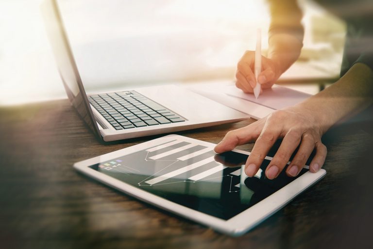 Person using a pen, tablet, and laptop.