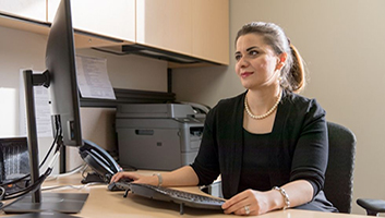 Professor Maryam Ghasmeaghaei sitting at a desk analyzing data