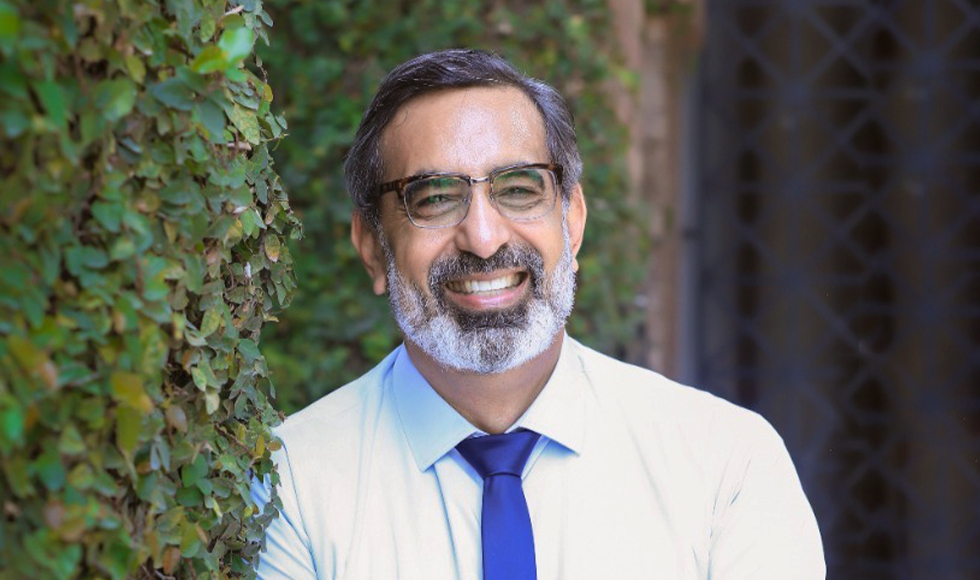 Dr Arshad Ahmad smiling in front of a campus building