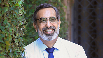 EMBA Professor Dr Arshad Ahmad smiling in front of a campus building