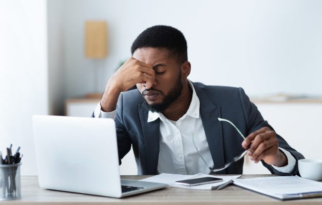 Businessman massaging his nose bridge, tired of work and struggling mental health