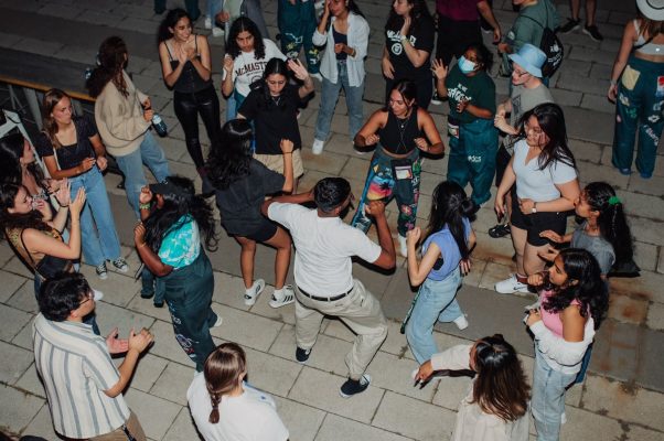 Students dancing in a crowd outdoors at night