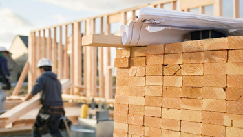 Stacked Lumber and Blueprints at a Construction Site