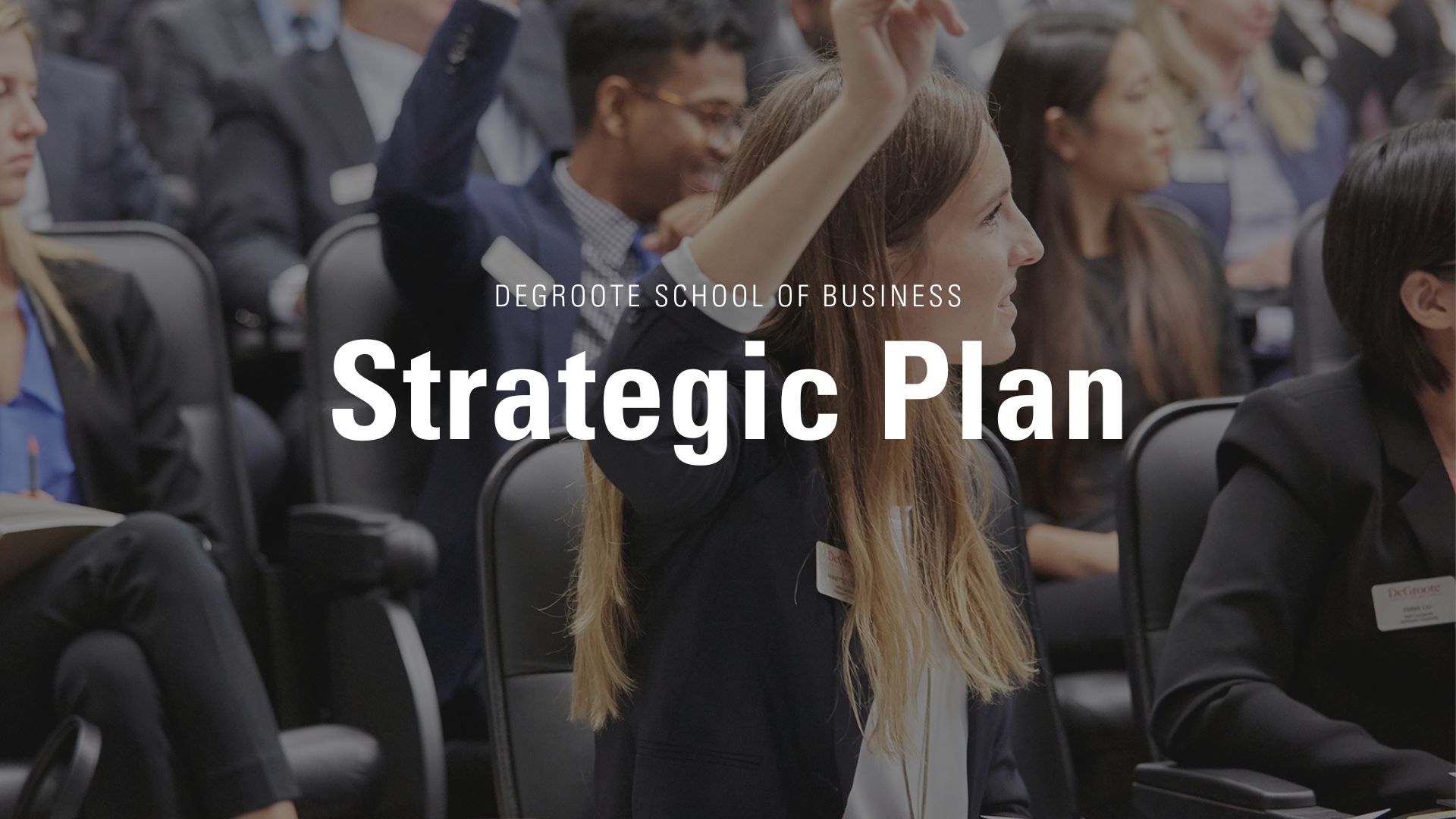 Strategic Plan Hero Image that has the text "DeGroote School of Business Strategic Plan". The image behind is a DeGroote student raising her hand to ask a question.