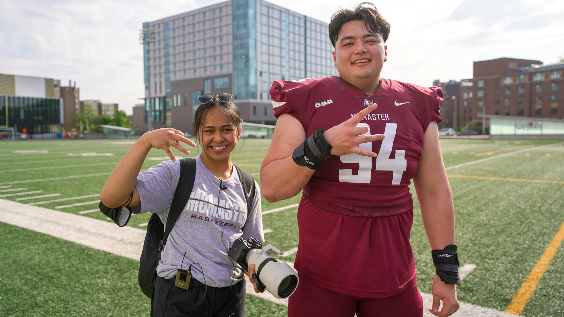 Alex Cheng posing with fellow Asian Pacific Islander Heritage Month founding member Arianne Soriano on the football field.