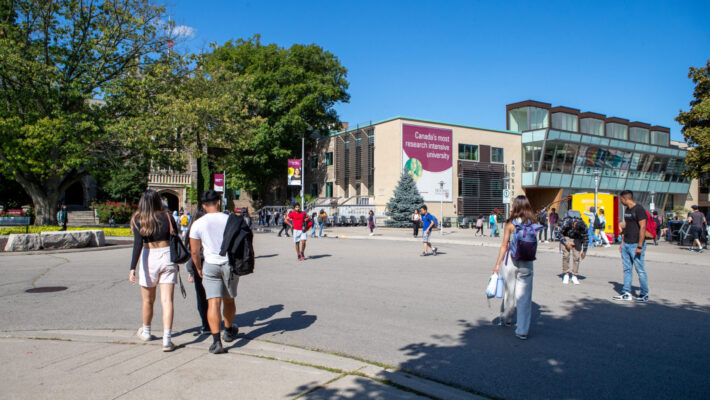 Students walking around the McMaster University campus in front of the McMaster University Student Centre.